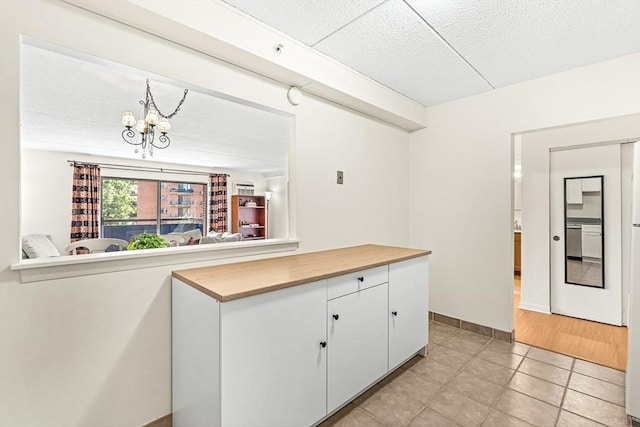 32 Whites Ave Unit F6605, Watertown, MA 02472 - kitchen with a chandelier, light tile patterned floors, white cabinets, wooden counters, and a textured ceiling