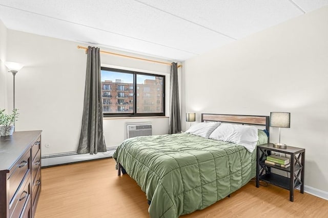 32 Whites Ave Unit F6605, Watertown, MA 02472 - bedroom featuring baseboard heating, light wood-style floors, and a wall mounted AC