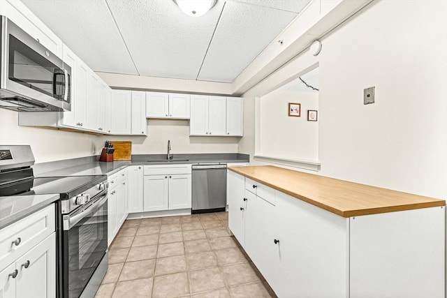 32 Whites Ave Unit F6605, Watertown, MA 02472 - kitchen featuring stainless steel appliances, white cabinets, wood counters, a center island, and a textured ceiling