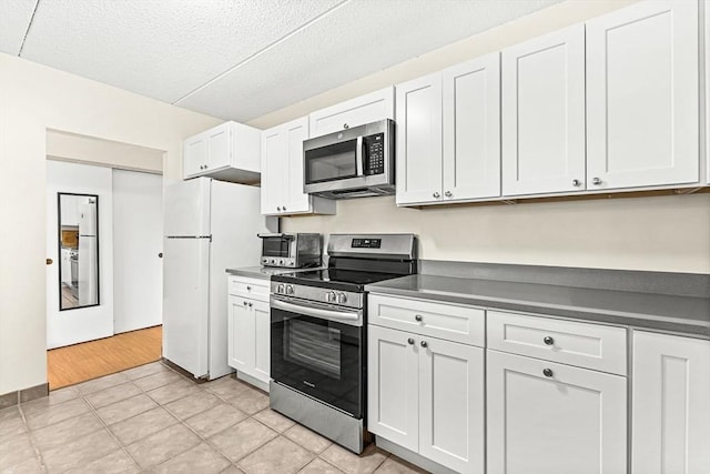 32 Whites Ave Unit F6605, Watertown, MA 02472 - kitchen with stainless steel appliances, white cabinets, dark countertops, a textured ceiling, and light tile patterned flooring