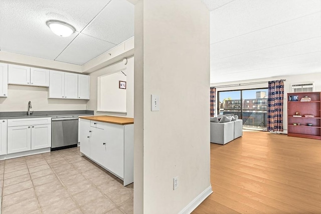 32 Whites Ave Unit F6605, Watertown, MA 02472 - kitchen with stainless steel dishwasher, white cabinetry, open floor plan, and light wood-style flooring
