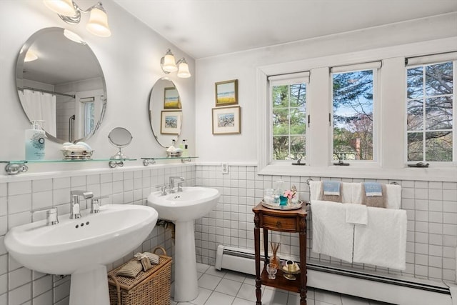 bathroom with a sink, a wainscoted wall, tile patterned flooring, and tile walls