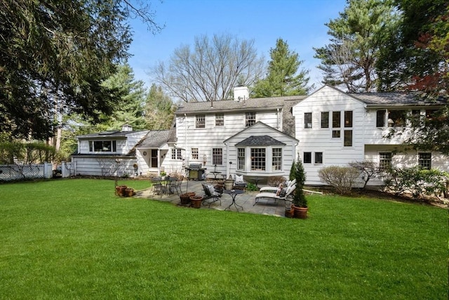 back of property with a lawn, fence, a chimney, and a patio area