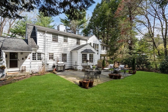 back of property with a lawn, a chimney, and a patio