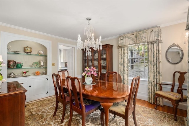 dining room featuring light wood-style floors, crown molding, and a notable chandelier