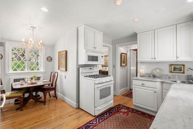 kitchen featuring a sink, white cabinetry, a chandelier, and white appliances