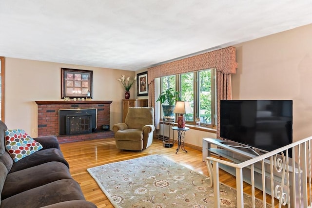 living room with a brick fireplace and wood finished floors