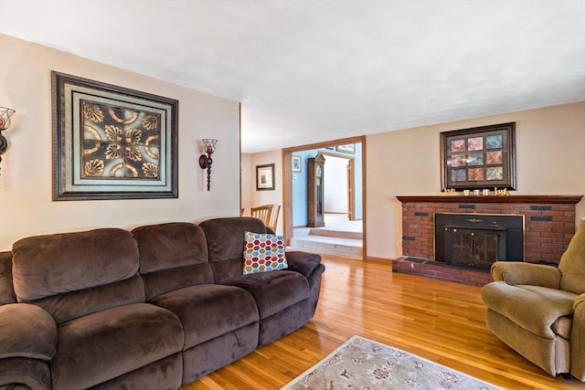 living room with light wood-style floors and a brick fireplace