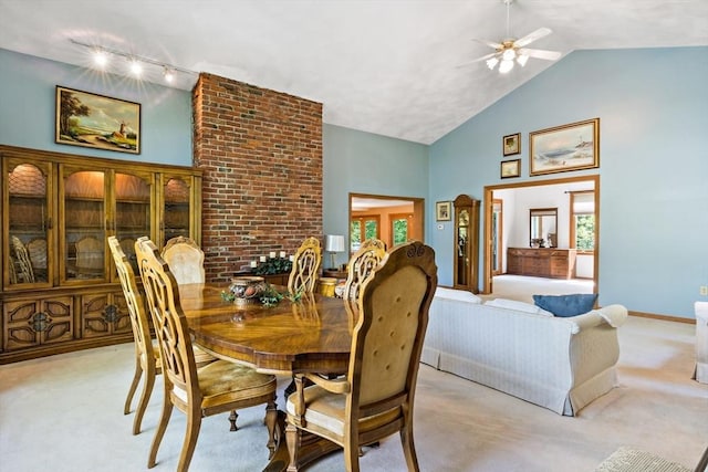 dining space featuring light carpet, high vaulted ceiling, rail lighting, a ceiling fan, and baseboards