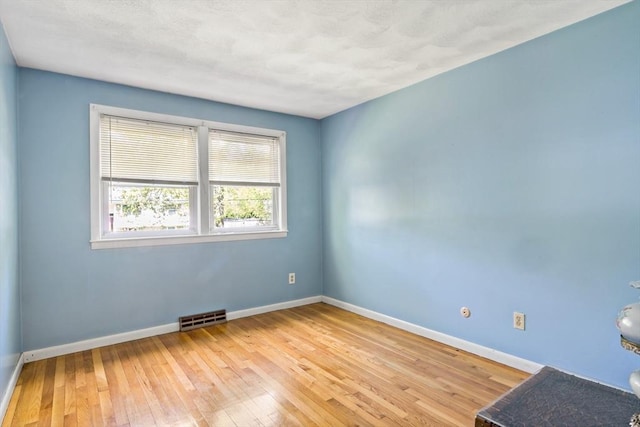 spare room featuring light wood-style flooring and baseboards