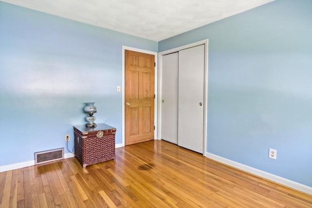 unfurnished bedroom with baseboards, light wood finished floors, and a closet