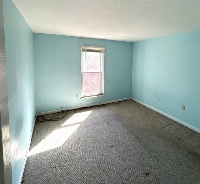 unfurnished room with carpet flooring and baseboards