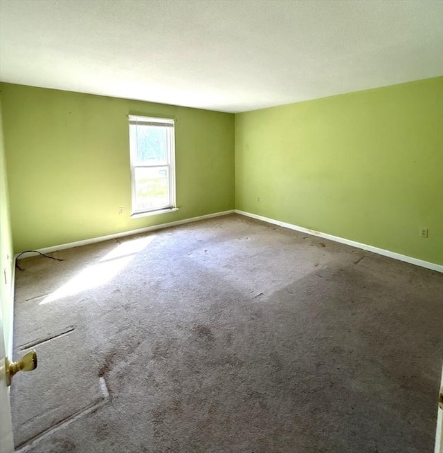 unfurnished room with baseboards and carpet