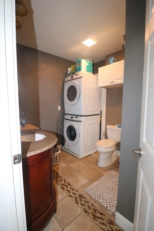 laundry area featuring stacked washer / drying machine and light tile patterned floors