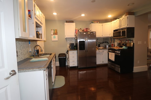 kitchen with appliances with stainless steel finishes, decorative backsplash, white cabinetry, dark hardwood / wood-style flooring, and sink