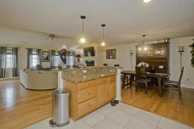 717 Northampton St Unit 41, Holyoke, MA 01040 - kitchen featuring a glass covered fireplace, ceiling fan, light wood finished floors, a textured ceiling, and decorative light fixtures