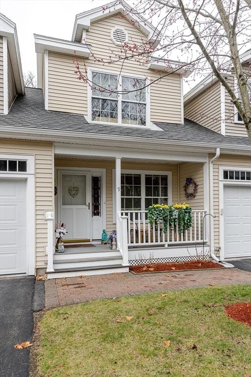 view of front of house with a garage, covered porch, a shingled roof, and driveway