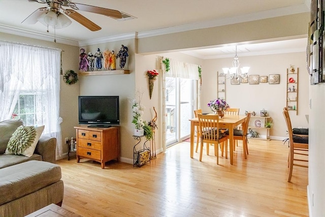 interior space featuring crown molding, plenty of natural light, ceiling fan with notable chandelier, and light wood finished floors