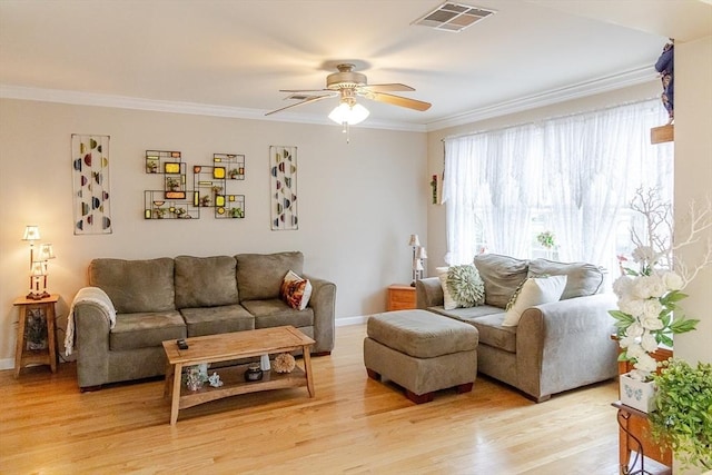 living room with visible vents, crown molding, baseboards, ceiling fan, and light wood-style flooring