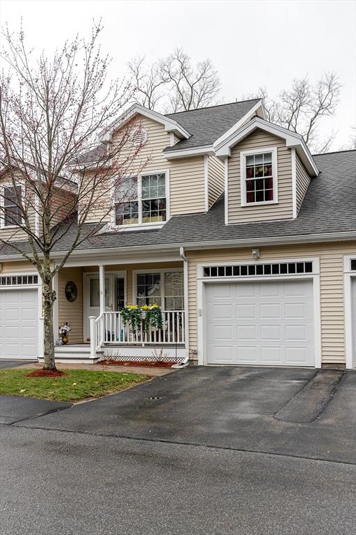 traditional home featuring a garage, a shingled roof, a porch, and aphalt driveway