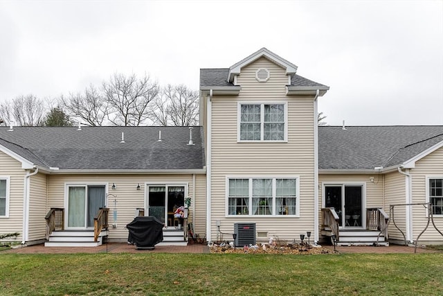 back of property with a lawn, a shingled roof, and entry steps