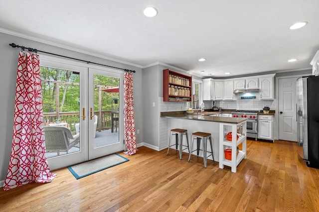 kitchen with appliances with stainless steel finishes, a peninsula, ornamental molding, a sink, and open shelves