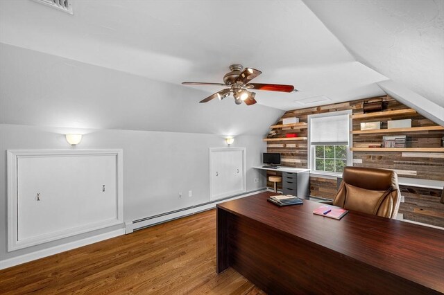 home office with lofted ceiling, ceiling fan, wood finished floors, a baseboard radiator, and wooden walls