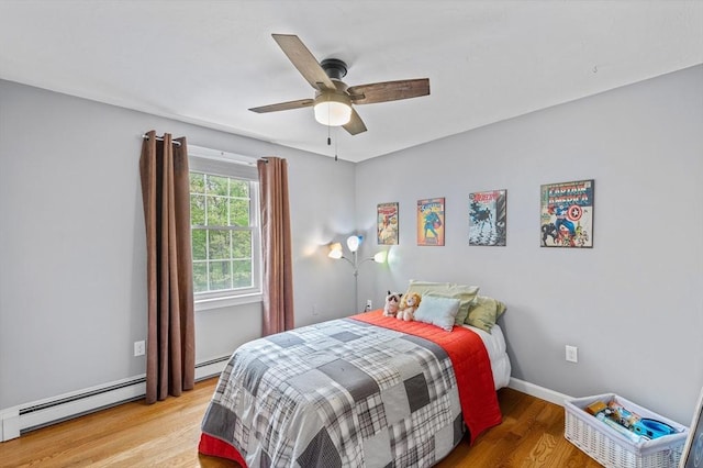 bedroom with wood finished floors, baseboard heating, ceiling fan, and baseboards