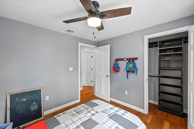 bedroom with wood finished floors, a closet, a spacious closet, and baseboards