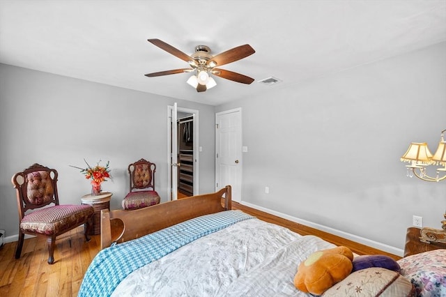 bedroom featuring baseboards, wood finished floors, a ceiling fan, and a chandelier