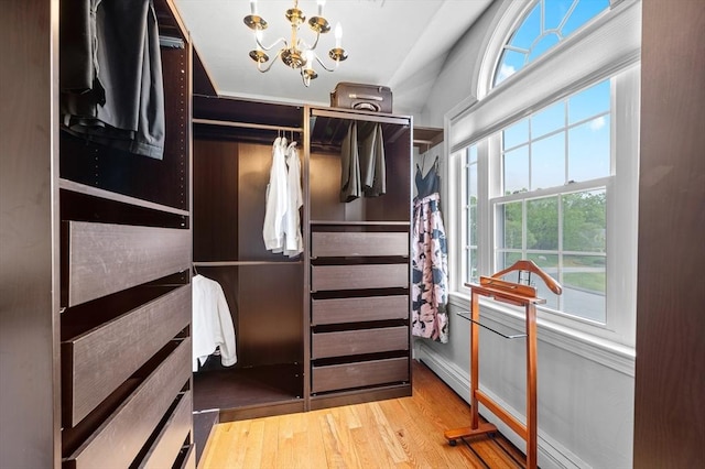 walk in closet with a chandelier, wood finished floors, and a baseboard heating unit
