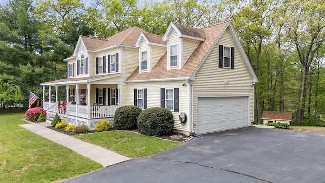 view of front of property with covered porch, an attached garage, asphalt driveway, a shingled roof, and a front lawn