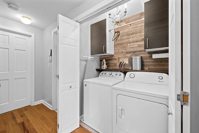 washroom featuring cabinet space, separate washer and dryer, light wood-type flooring, and baseboards