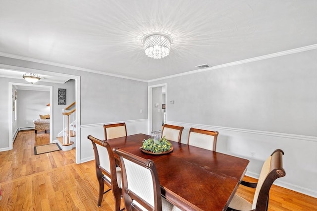 dining area featuring stairs, a chandelier, light wood-style floors, and ornamental molding