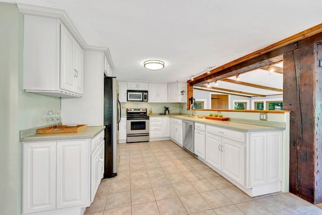 26 Beacon St, Amesbury, MA 01913 - kitchen with stainless steel appliances, light countertops, white cabinets, and light tile patterned flooring