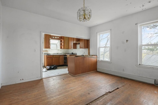 kitchen featuring baseboard heating, plenty of natural light, pendant lighting, and an inviting chandelier