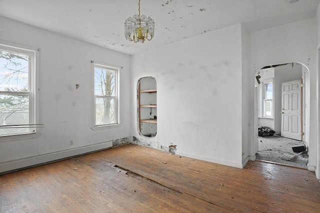 spare room featuring hardwood / wood-style flooring, plenty of natural light, an inviting chandelier, and a baseboard heating unit