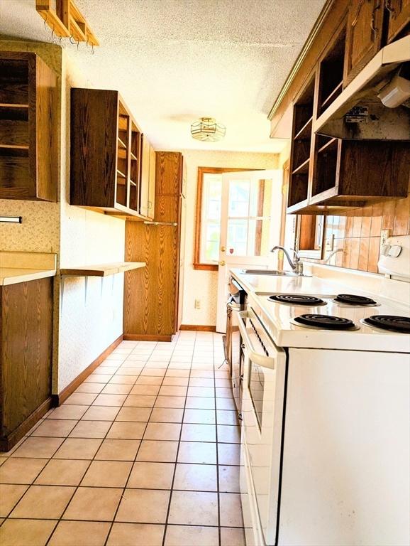 kitchen featuring light tile patterned floors, a sink, open shelves, a textured ceiling, and white electric range