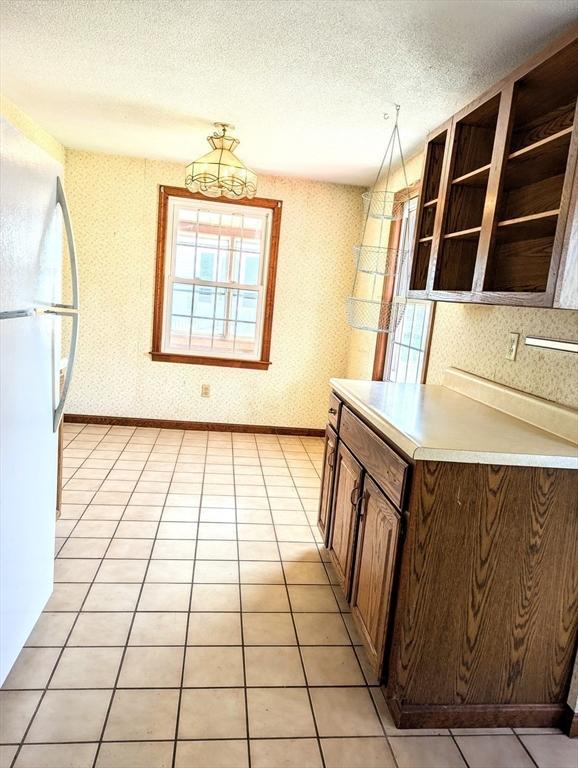 kitchen featuring light tile patterned floors, freestanding refrigerator, open shelves, a textured ceiling, and light countertops