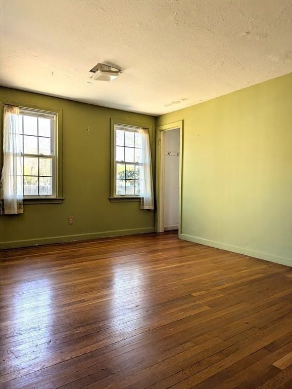unfurnished room with baseboards, wood-type flooring, and a textured ceiling