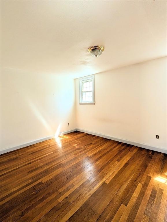 spare room with baseboards and hardwood / wood-style floors
