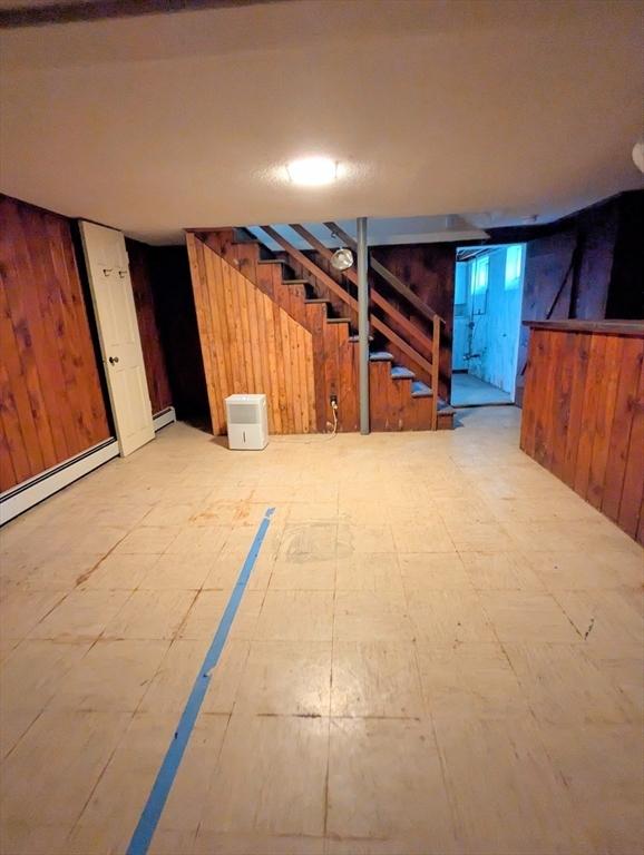 finished below grade area with wooden walls, stairs, and baseboard heating