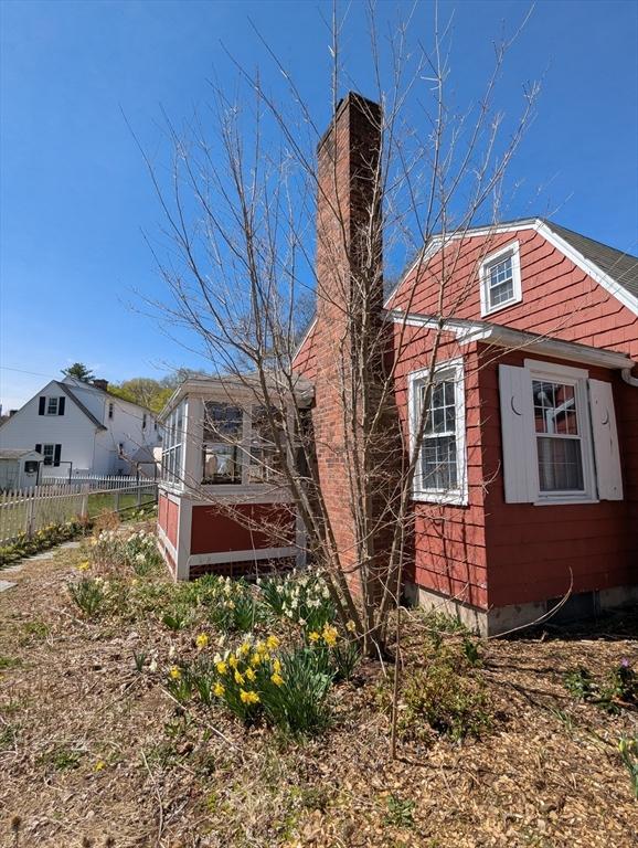 view of side of home with a chimney and fence