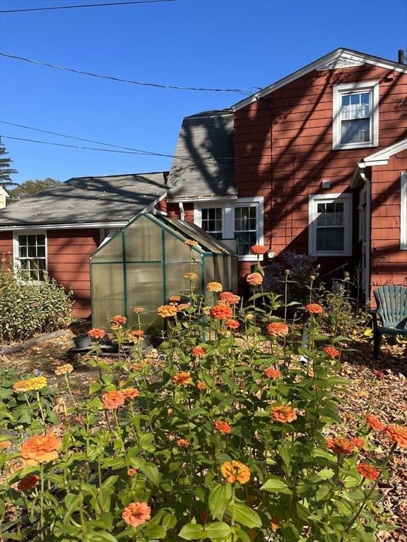 view of side of home with a greenhouse and an outdoor structure
