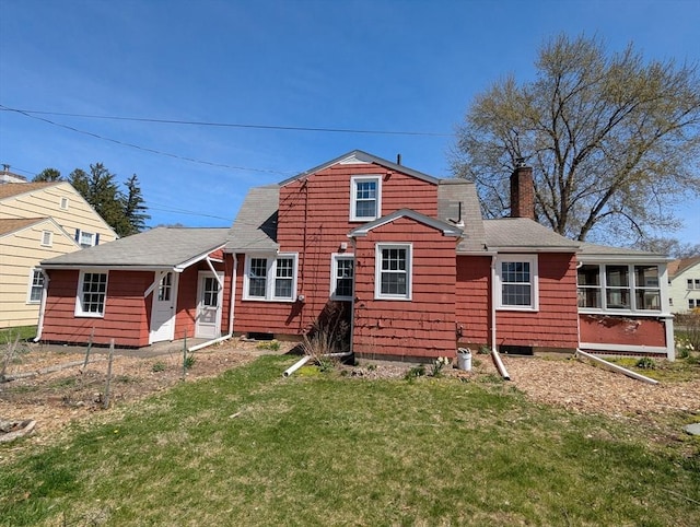 rear view of property with a chimney, a yard, a sunroom, and a shingled roof