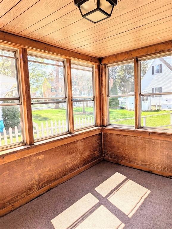 unfurnished sunroom featuring a wealth of natural light, wood ceiling, and carpet