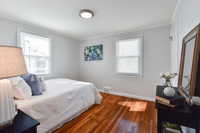 bedroom featuring hardwood / wood-style flooring, baseboards, visible vents, and ornamental molding