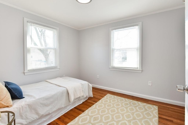 bedroom featuring baseboards, wood finished floors, and ornamental molding