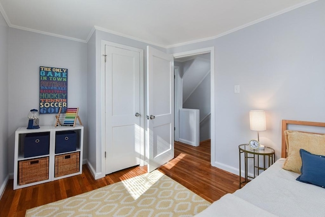 bedroom with a closet, baseboards, wood finished floors, and ornamental molding