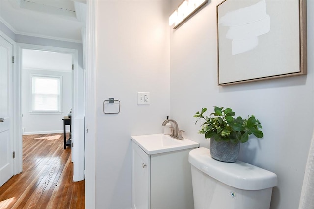 bathroom with baseboards, toilet, ornamental molding, hardwood / wood-style floors, and vanity